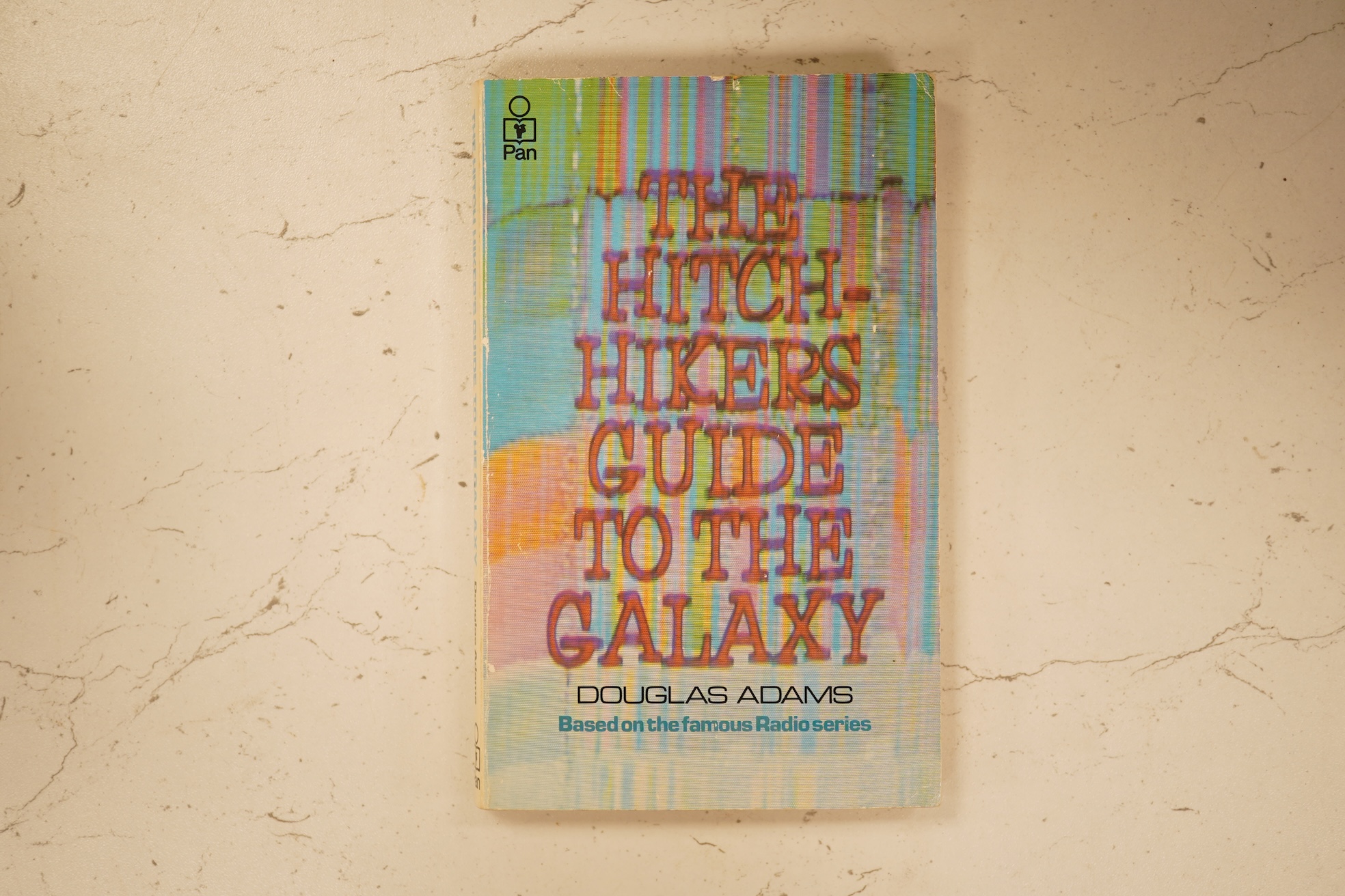 Adams, Douglas - The Hitch Hiker's Guide to the Galaxy. first edition, 2nd printing. half title/radio series leaf; paperback, sm. 8vo. Pan Books, 1979. *published same year as first and with a differently designed cover;